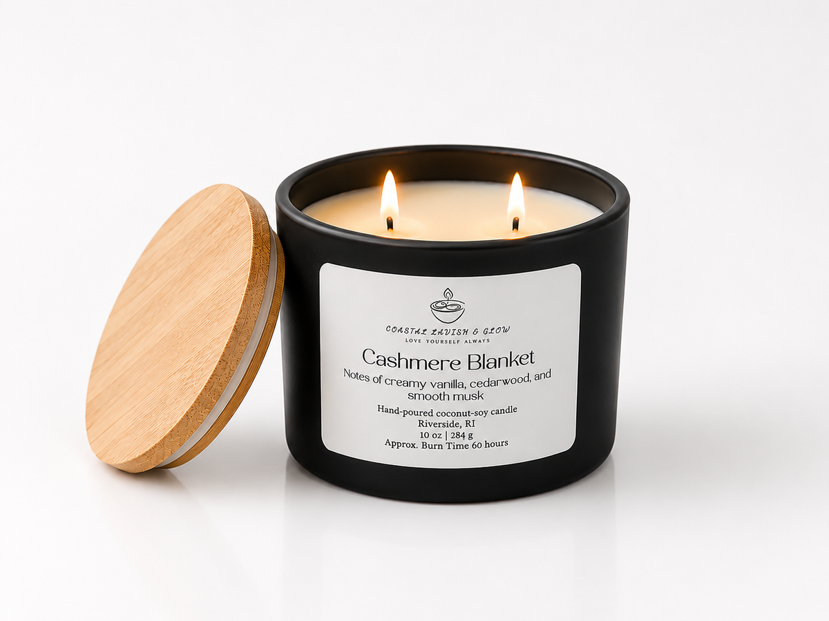 "Cashmere Blanket" candle in a black candle jar with wooden lid and visible flames on a white background