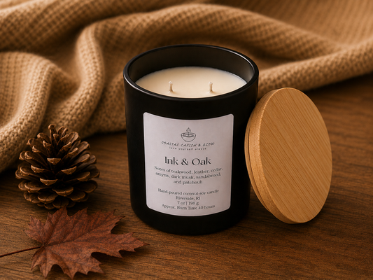 Candle labeled 'Ink & Oak' with a wooden lid and pine cone on a wooden surface