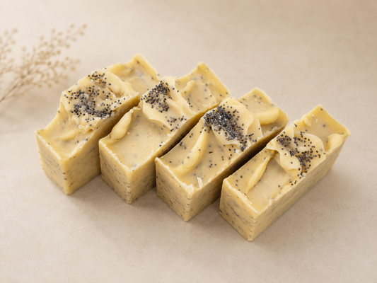 Four rectangular soap bars with poppy seeds on a beige background