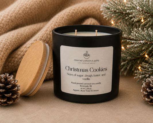 "Christmas Cookies" candle with a wooden lid on a textured surface with a Christmas tree in the background.
