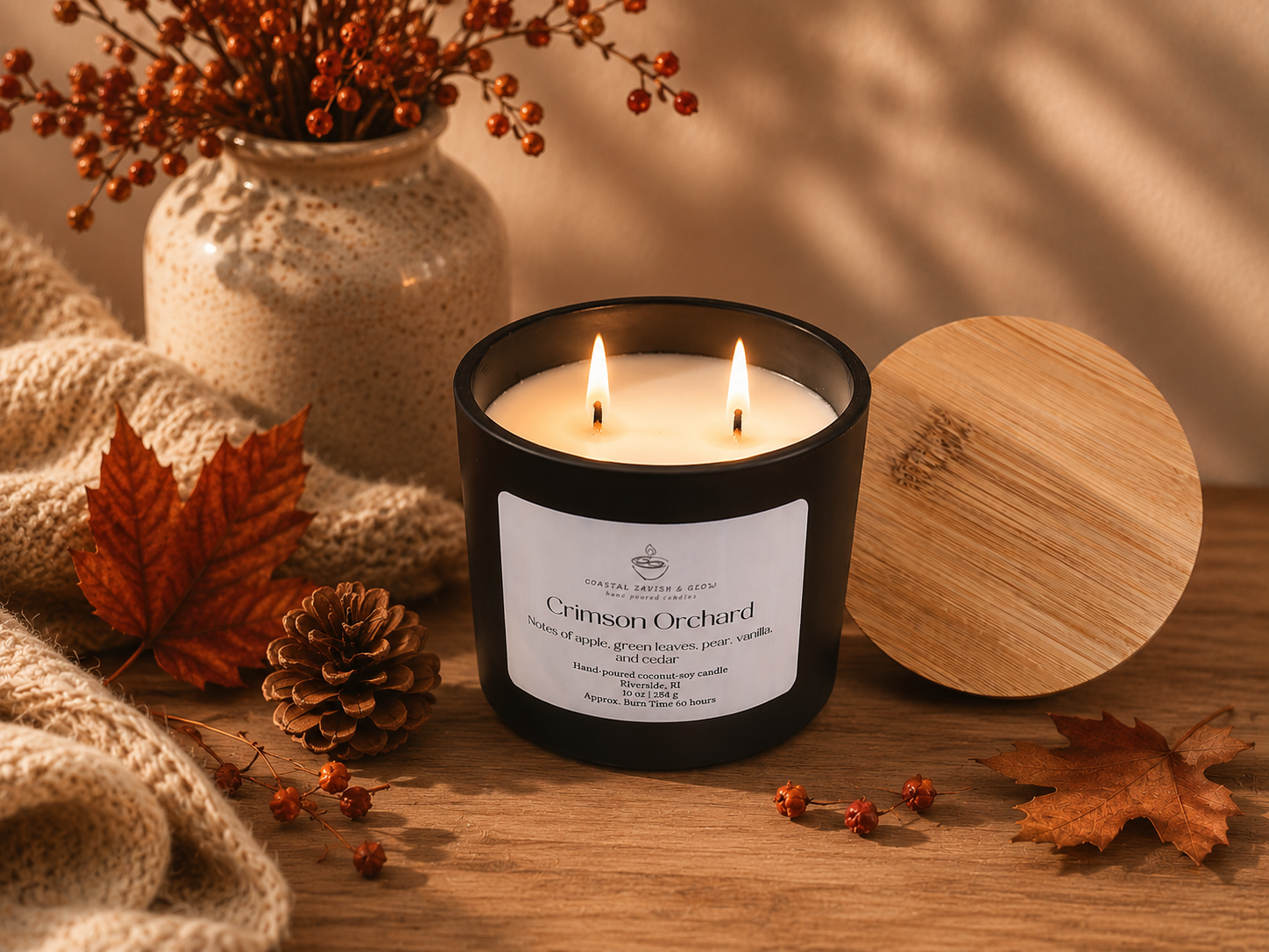 Candle labeled 'Crimson Orchard' with autumn decorations on a wooden surface