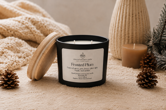 "Frosted Plum" candle with a label on a textured surface with decorative elements