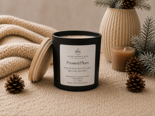 "Frosted Plum" candle with a label on a textured surface with decorative elements