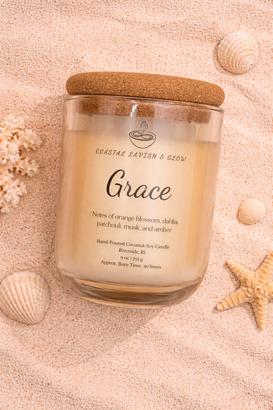 'Grace' candle on a sandy background with shells and starfish.  Orange Blossom, Dahlia, Patchouli, Musk, and Amber Scent