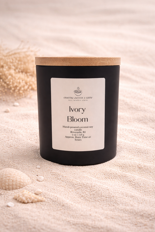 'Ivory Bloom' candle on a sandy background.  Notes of vanilla, green leaves, jasmine, sandalwood, musk scent