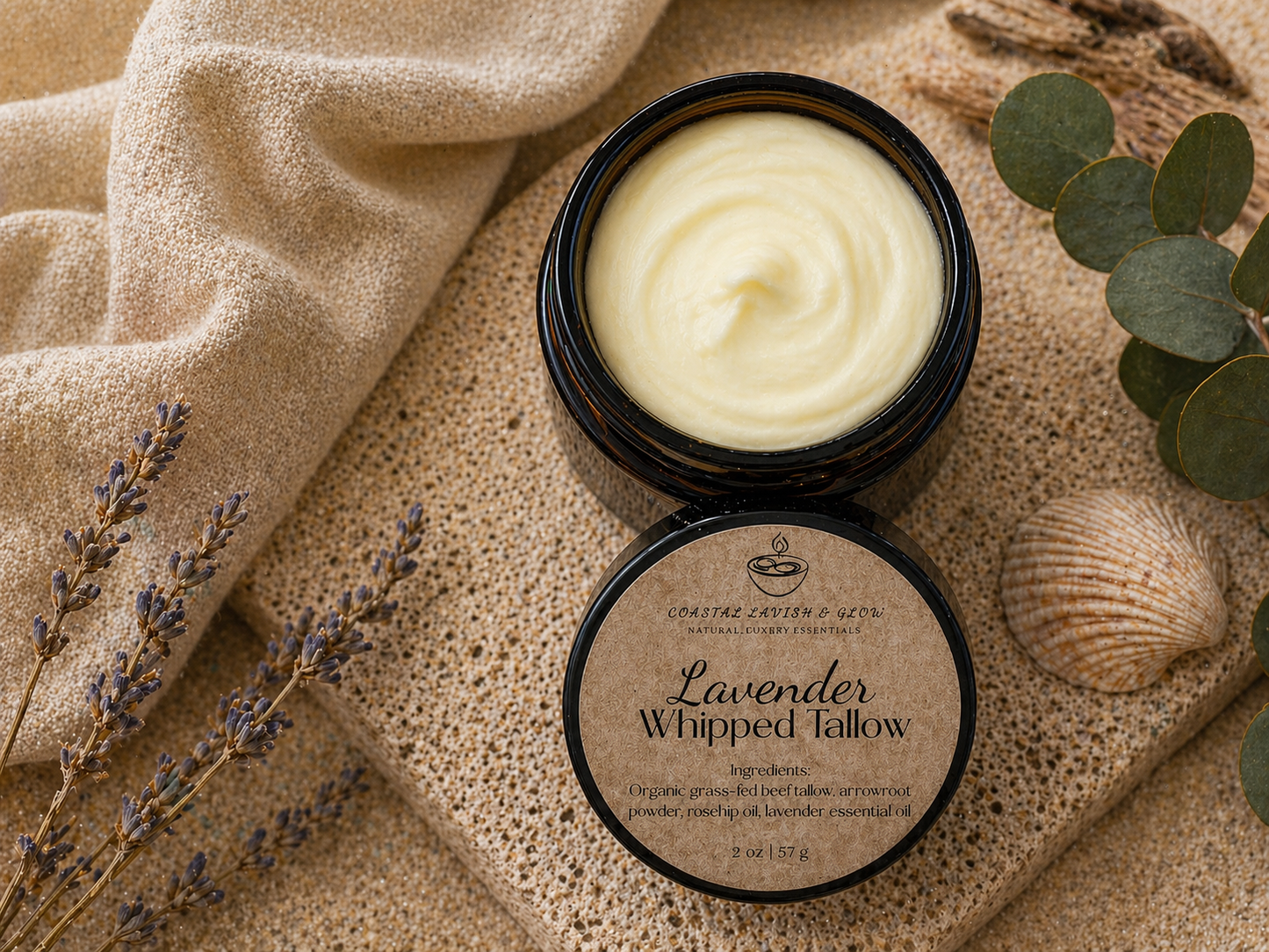 Lavender whipped tallow balm in a black container on a textured surface with eucalyptus leaves and lavender flowers.