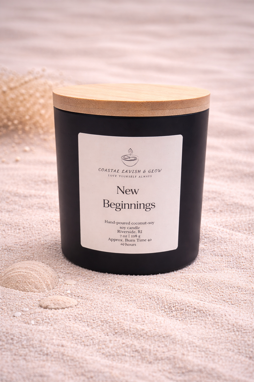 New Beginnings - Black candle with a wooden lid on a sandy surface.  Orange peel, ginger, nutmeg, cinnamon scent.