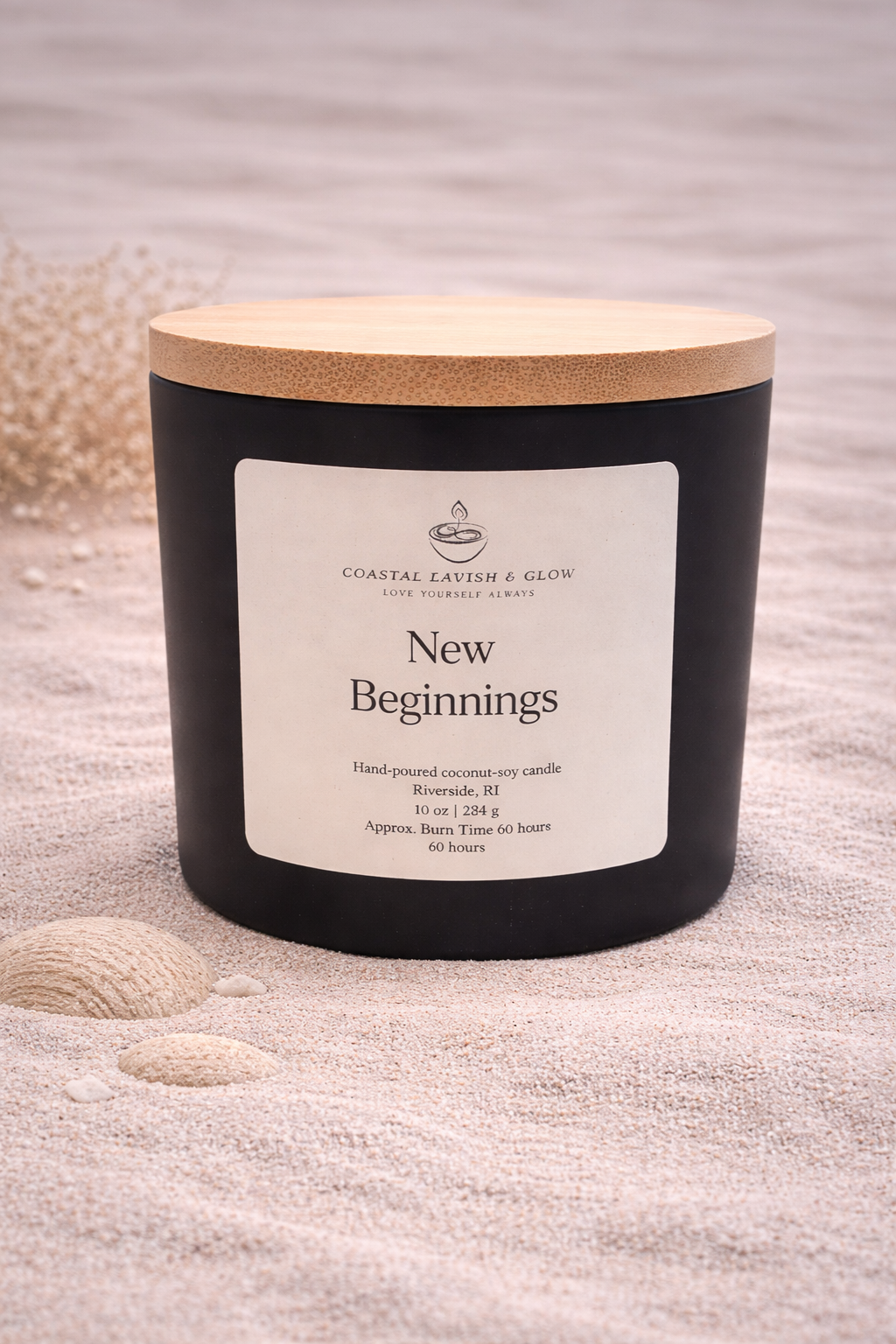 New Beginnings - black glass candle with a wooden lid on a sandy background.  Orange Peel, Ginger, Nutmeg, Cinnamon Scent