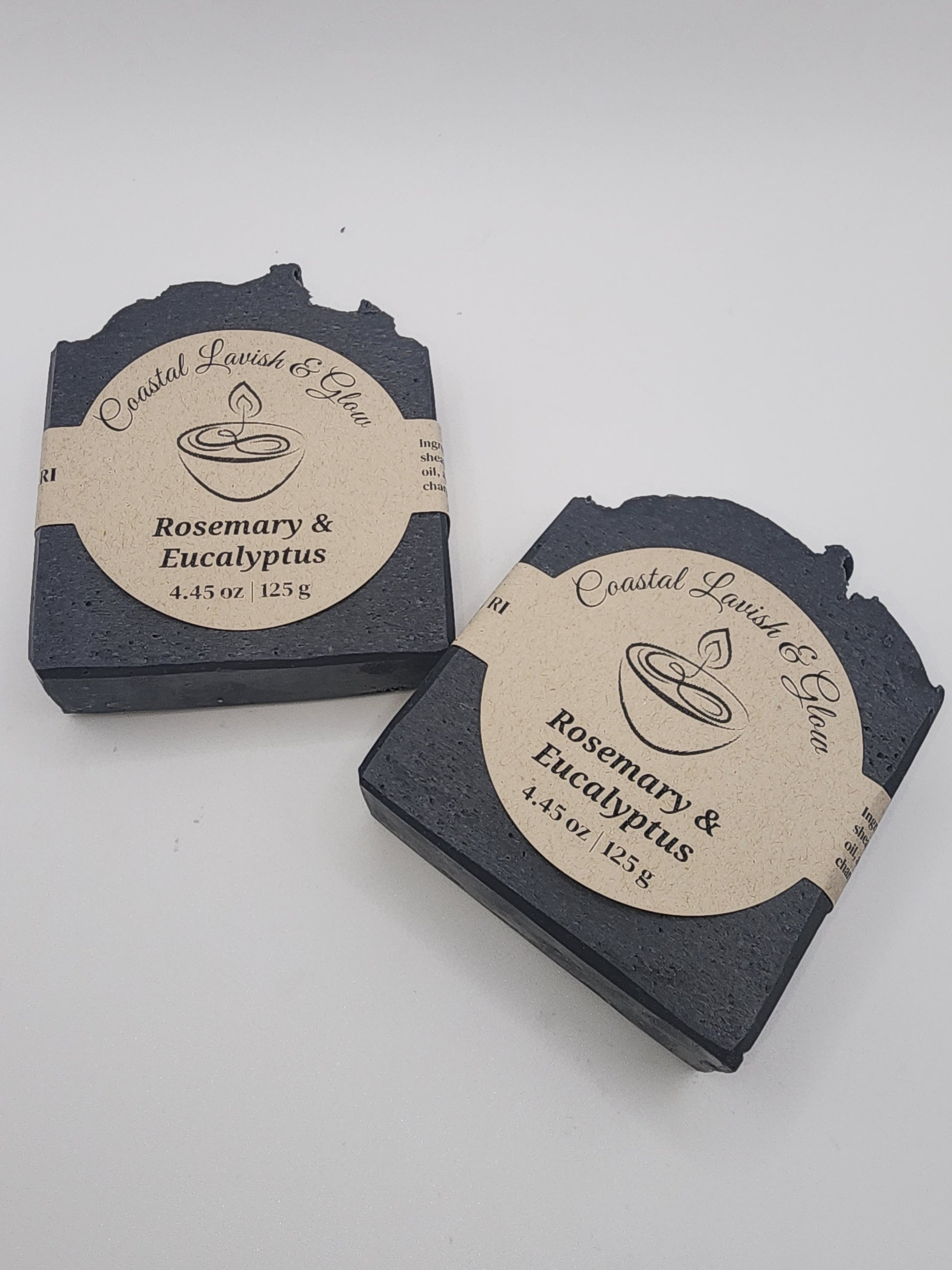 Two black soap bars with circular labels on a light gray background scented Rosemary and Eucalyptus