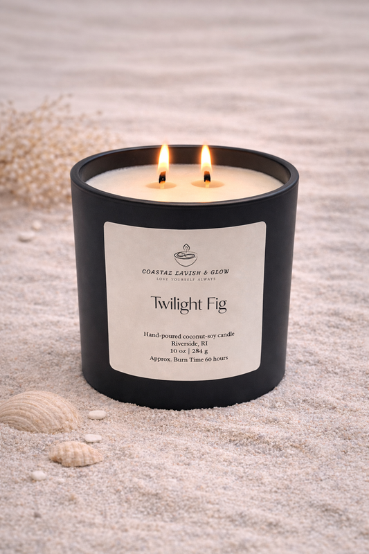 Twilight Fig candle in a black container on sand with seashells - citrus, plum, black cherry, amber scent