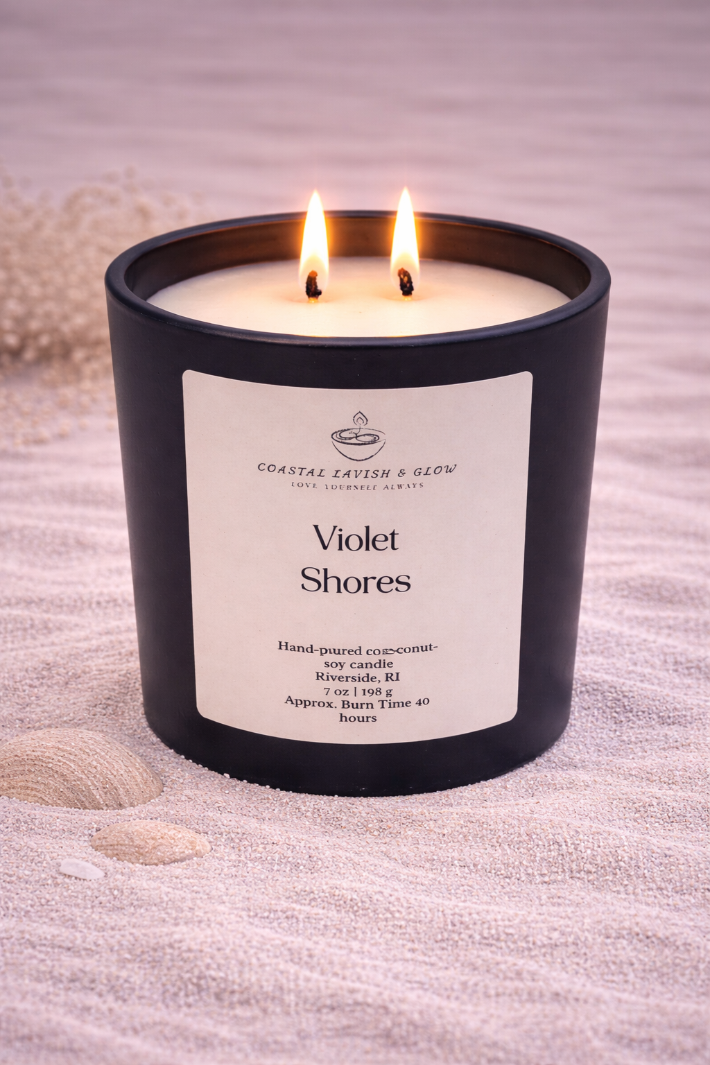 Violet Shores black glass candle with a wooden lid and label on a textured surface with shells.  Lavender and sage scent.