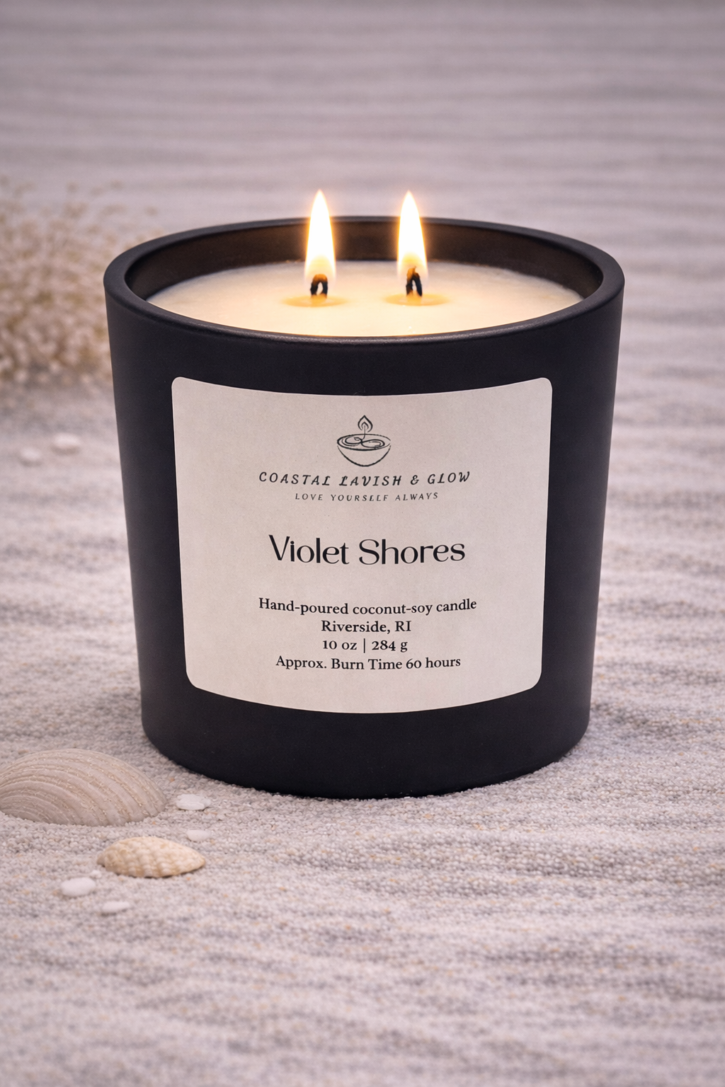 Violet Shores black glass candle with a wooden lid on a beachy surface.  Lavender and sage scent.