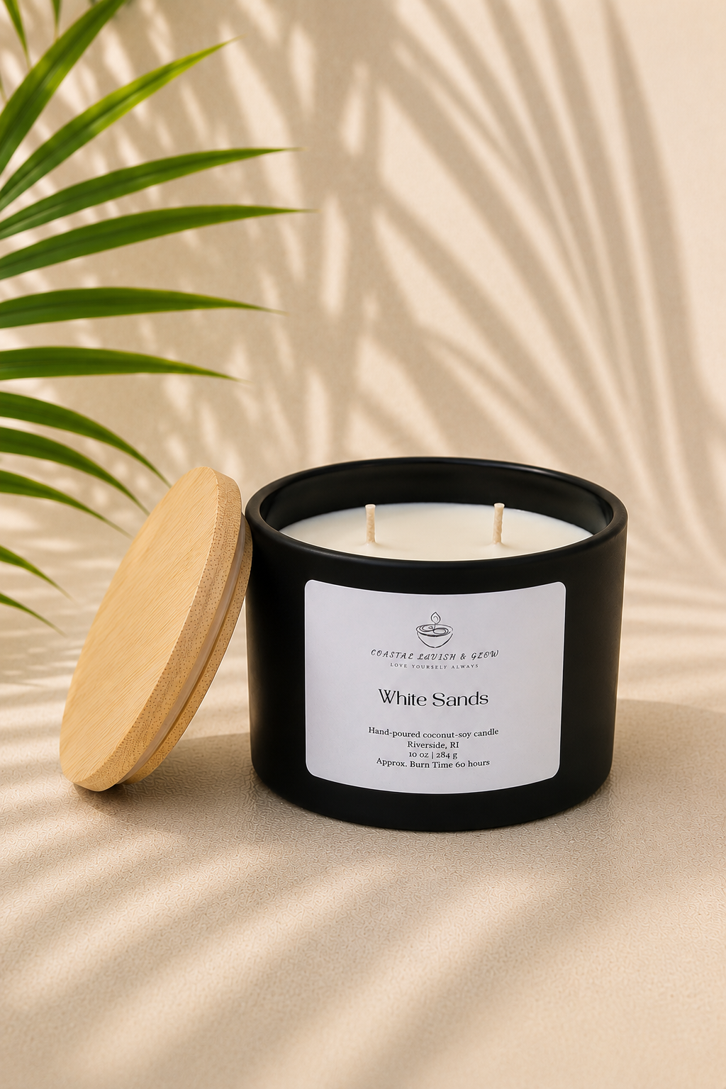 "White Sands" black candle with a wooden lid on a beige surface with a plant in the background
